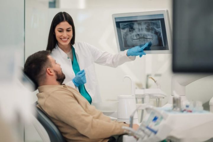 Smiling,Female,Dentist,Pointing,At,Teeth,X,Ray,On,Digital dentist near me