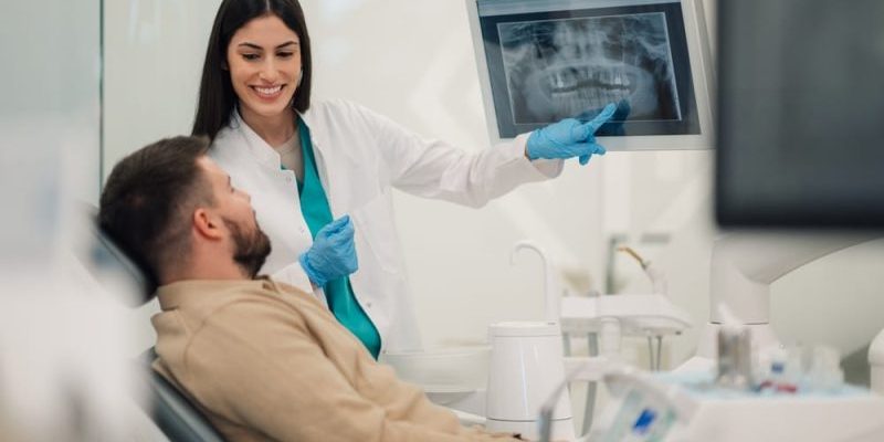 Smiling,Female,Dentist,Pointing,At,Teeth,X,Ray,On,Digital dentist near me